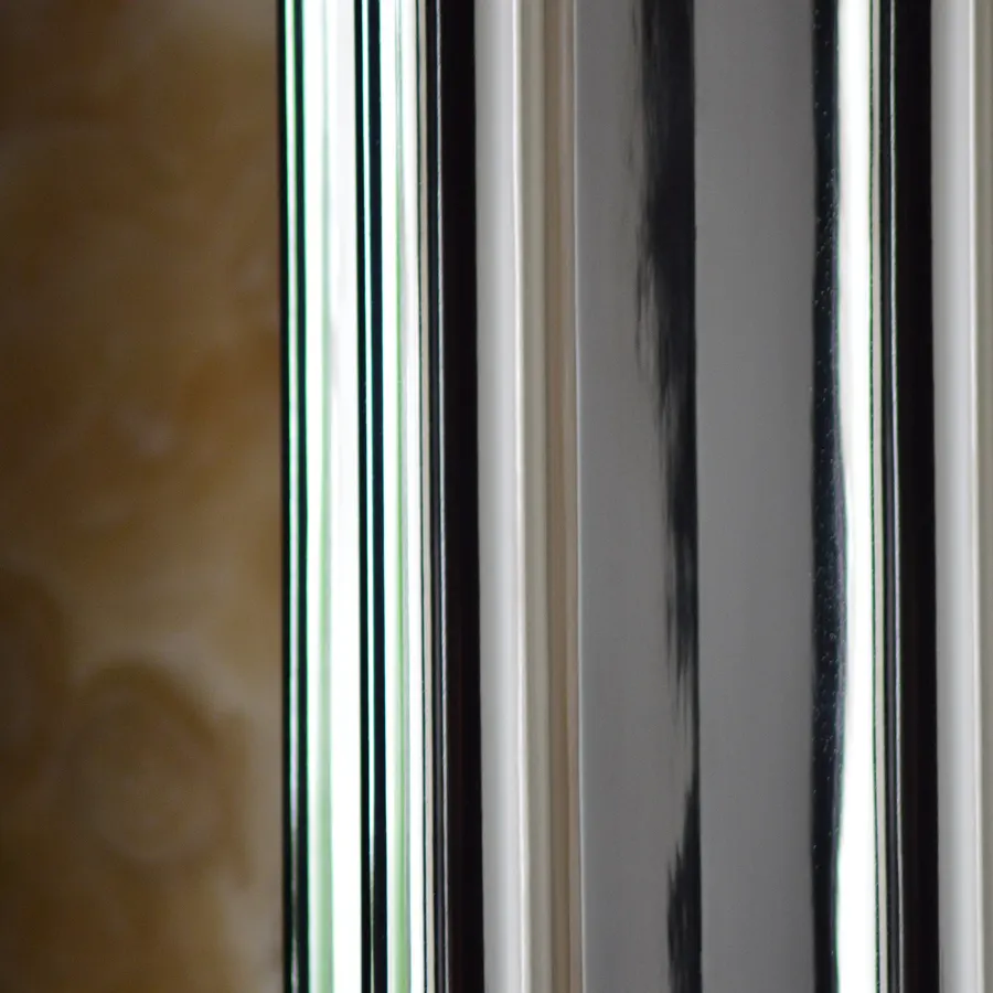 Close-up of a chrome-clad cruciform column in front of the veined onyx wall