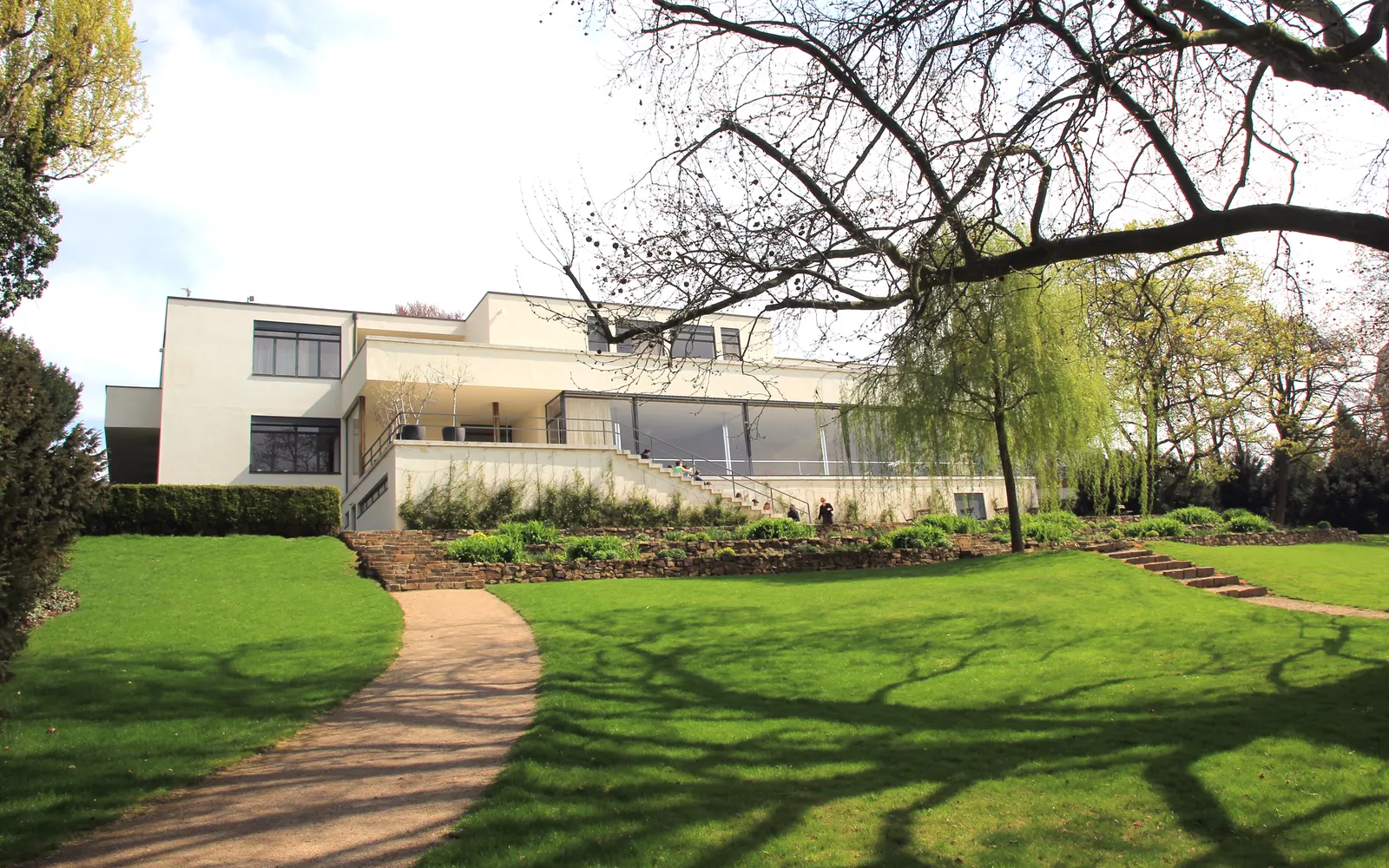 La fachada del jardín de la Villa Tugendhat sobre su césped en pendiente y el sendero curvo
