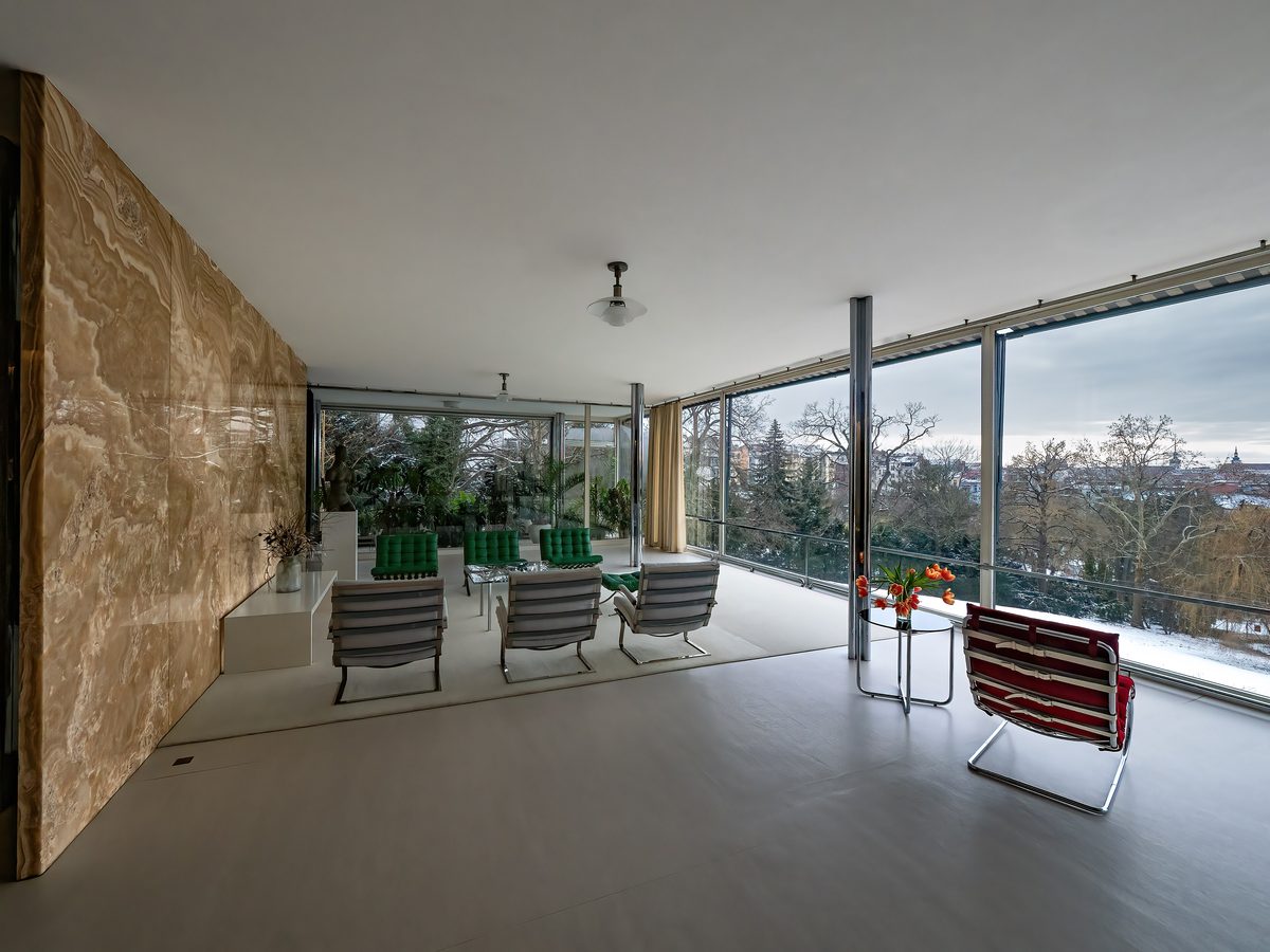 El salón principal de la Villa Tugendhat: el muro de ónix color miel dorada a la izquierda, el ventanal de altura completa al jardín a la derecha